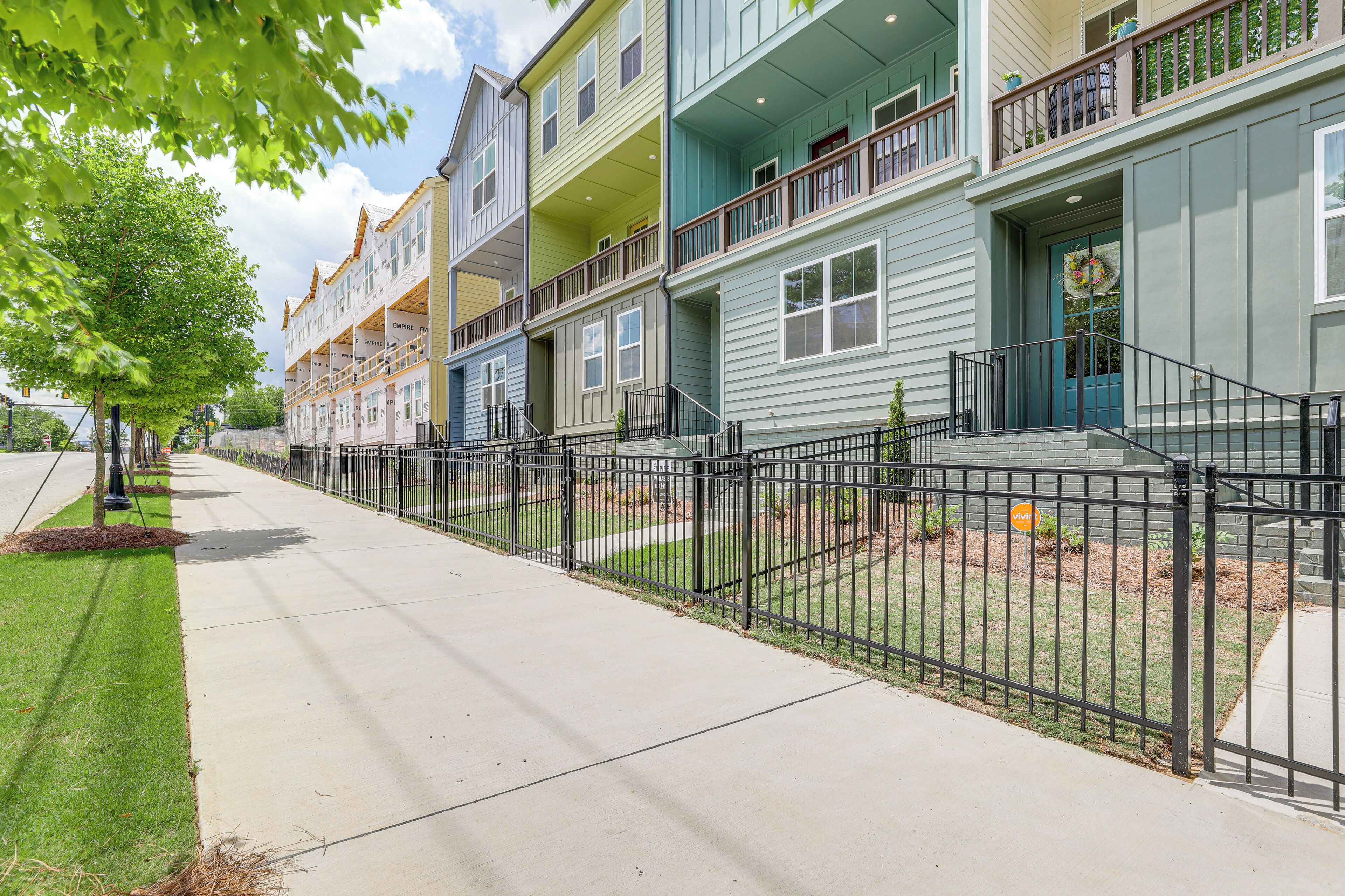 A row of townhouses with balconies, a gated driveway, and a well-maintained lawn.