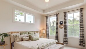 A bedroom with a large bed, bedside tables, a bench, and a window with curtains.
