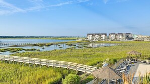 A coastal hotel with a boardwalk, beach chairs, and a view of the water. - Walk to Beach & Marsh: Condo in Murrells Inlet (Murrells Inlet)