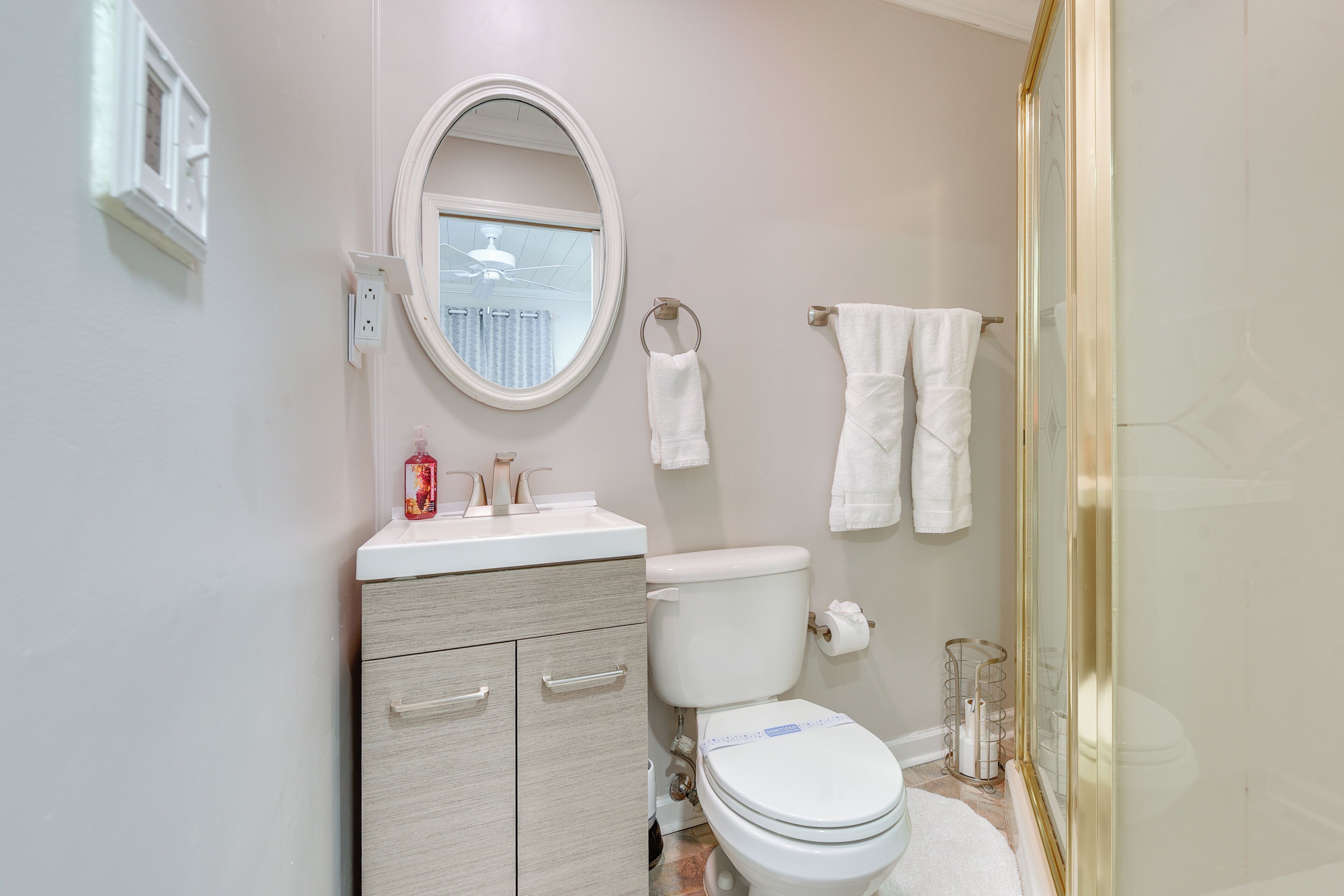 A bathroom with a toilet, a sink with a mirror, and a shower area.