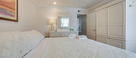 A bedroom with a large bed, a ceiling fan, a dresser, and a wardrobe.