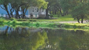A house with a porch, surrounded by trees and a pond. - Family-friendly Rock Island Home 5 Mi to Splashway (Rock Island)