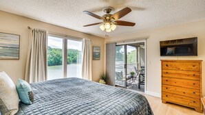 A bedroom with a bed, a ceiling fan, a dresser, and a balcony with a view of greenery. - Lake & Pool Access: Lazy Days Condo w/ Balcony! (Osage Beach)