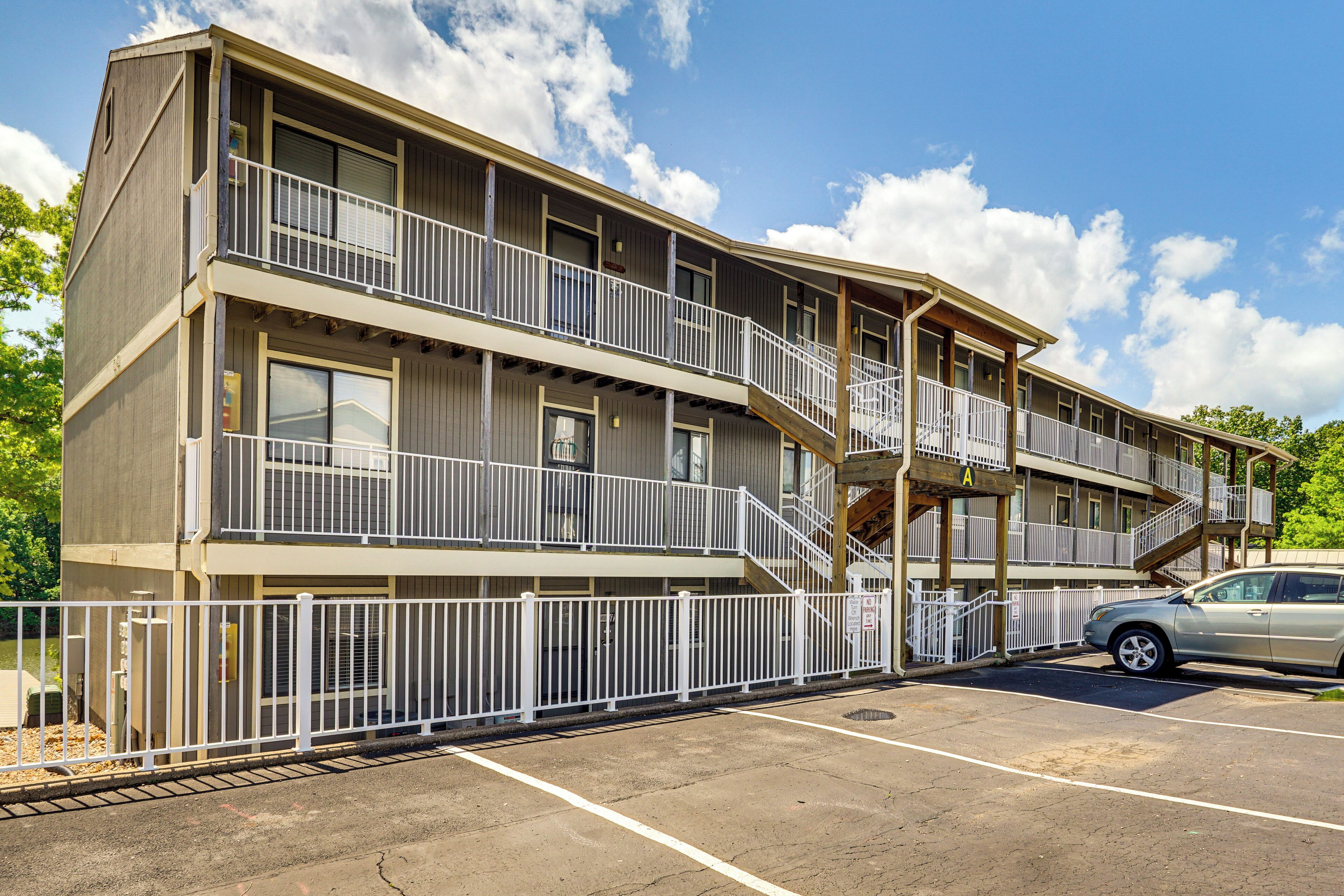 A multi-story hotel with balconies, a parking lot, and a clear sky.