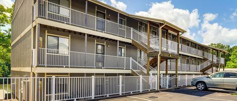 A multi-story hotel with balconies, a parking lot, and a clear sky.