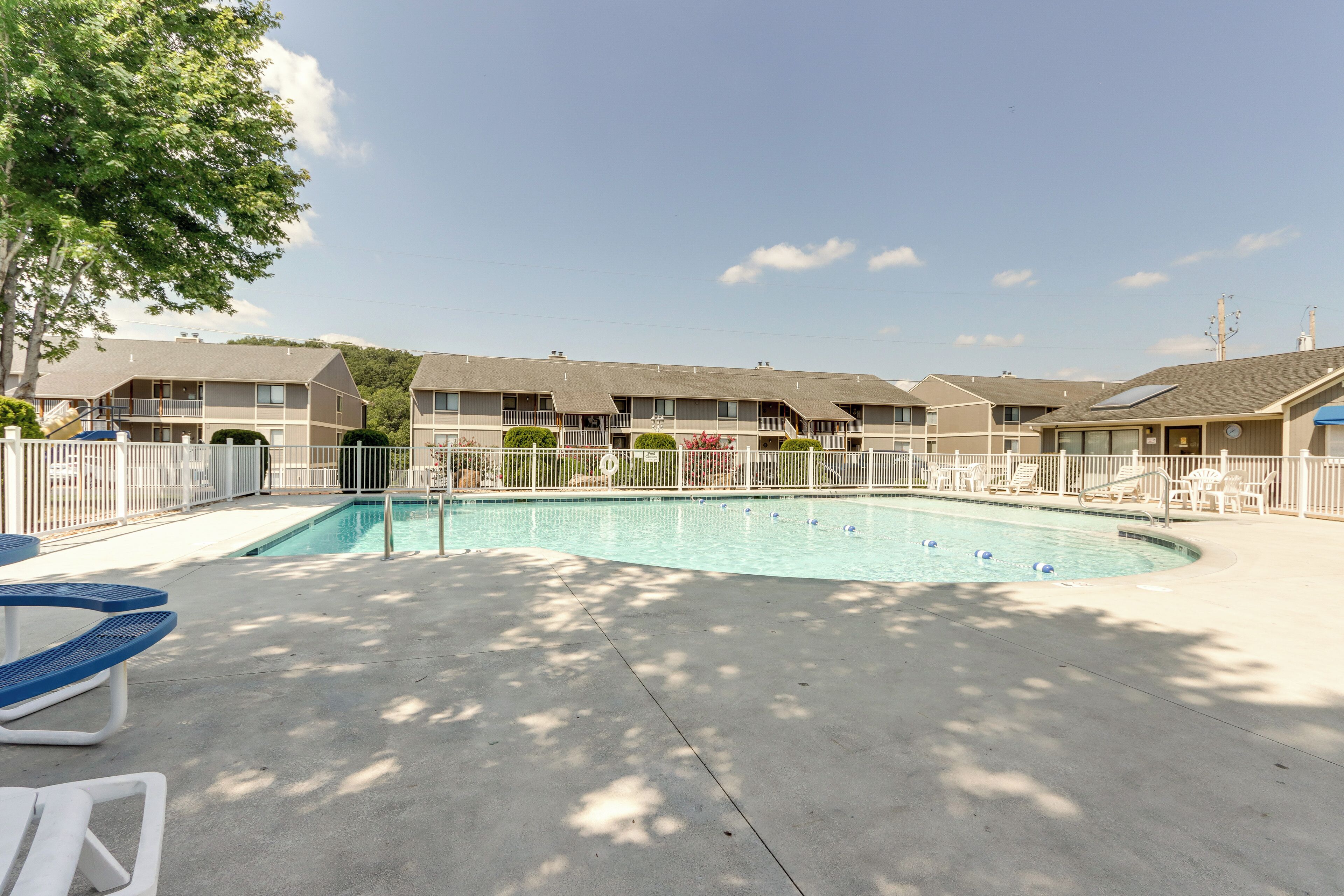 A hotel with a swimming pool, outdoor seating, and a fenced area.