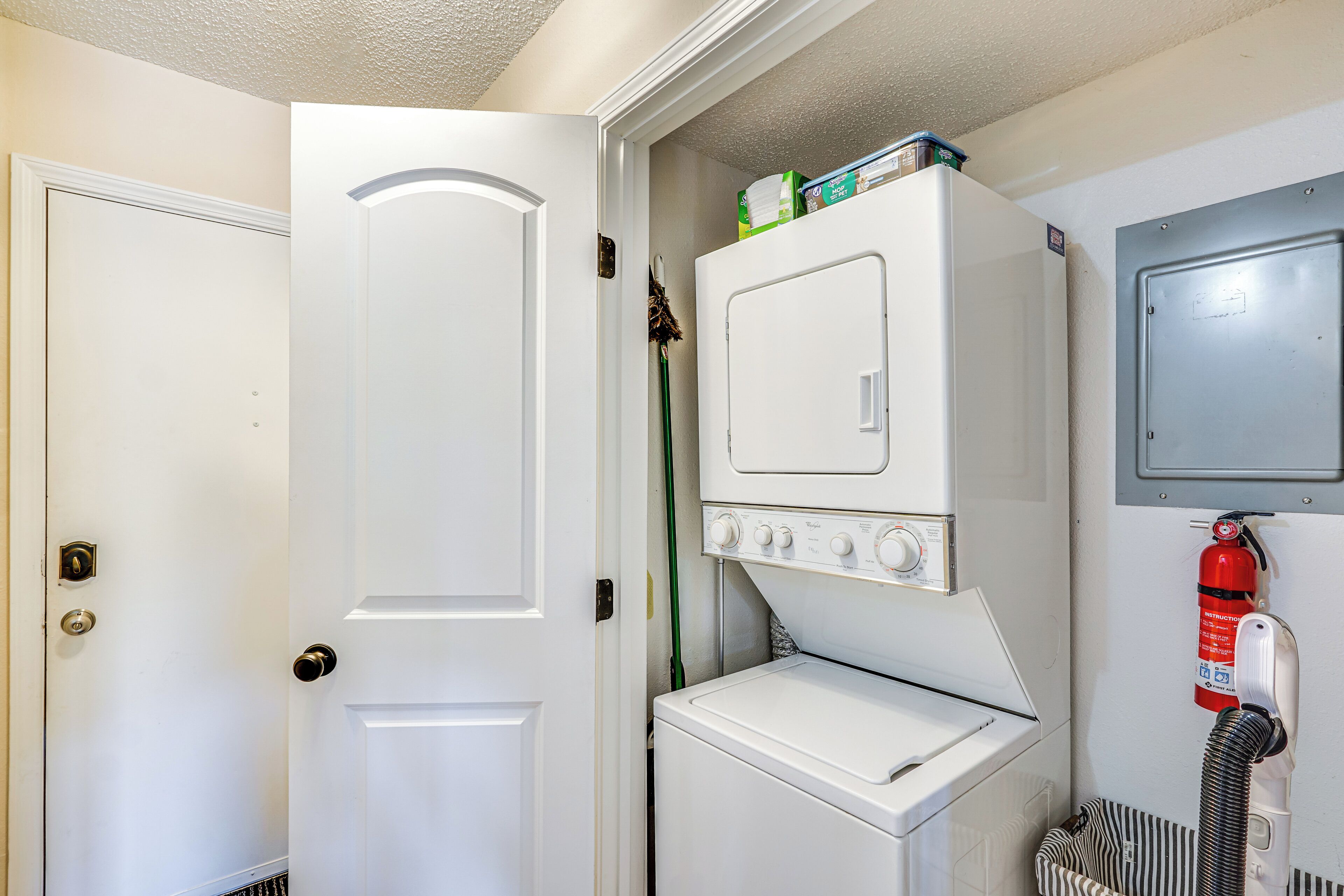 A laundry room with a washer and dryer, a fire extinguisher, and a door.