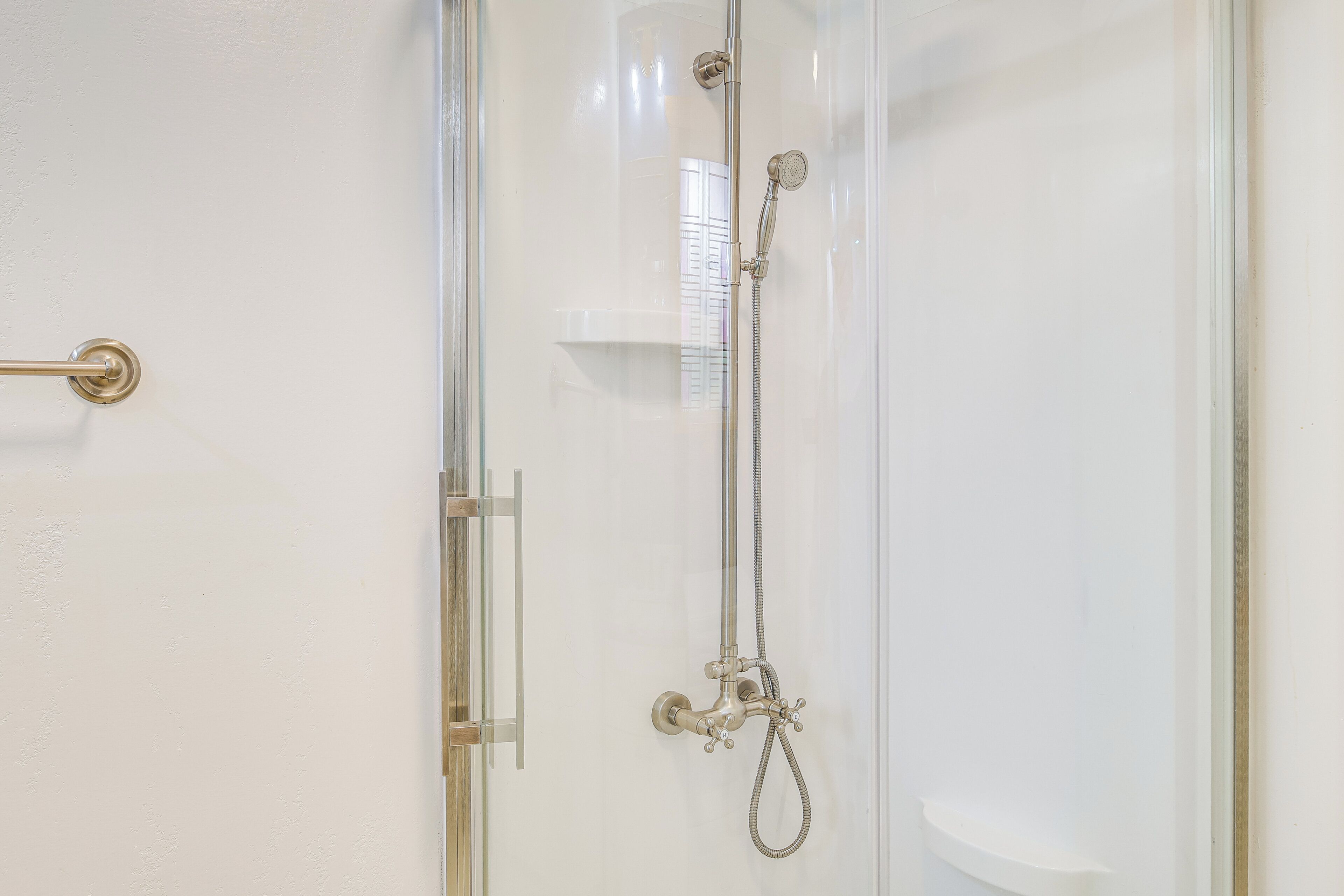 A shower with a handheld showerhead and a wall-mounted faucet.