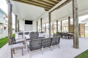 Une terrasse extérieure couverte, aménagée avec des meubles en osier, un coin bar et des piliers en bois.