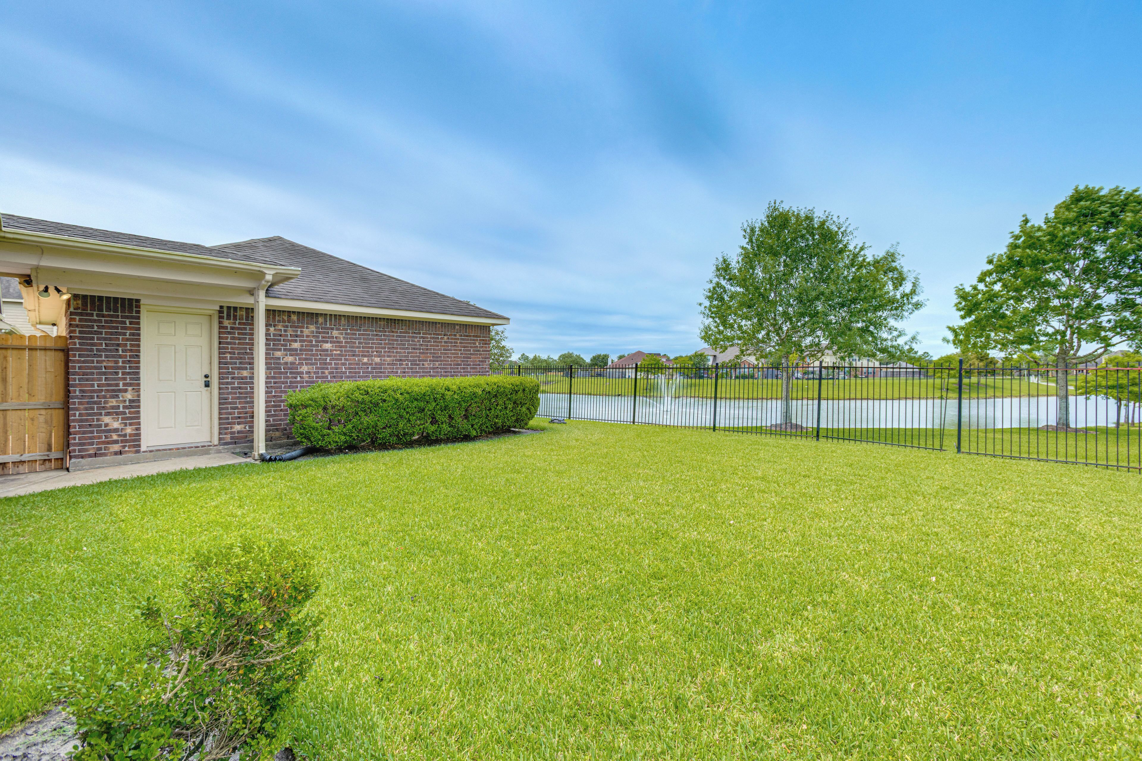 A residential property with a brick house, a well-maintained lawn, and a black metal fence.
