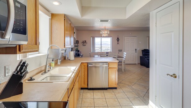 A modern kitchen with a dishwasher, wooden cabinets, a built-in microwave, and a large window providing natural light. - Pool Access & Mtn Views: Lake Havasu City Condo! (Lake Havasu City)