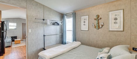 Une chambre avec un lit, un portant à vêtements et une porte donnant sur une autre pièce.