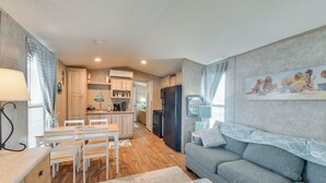 Une cuisine moderne avec des meubles en bois, un réfrigérateur et un coin repas avec des chaises blanches.