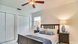 A bedroom with a bed, nightstands, a ceiling fan, and a window.