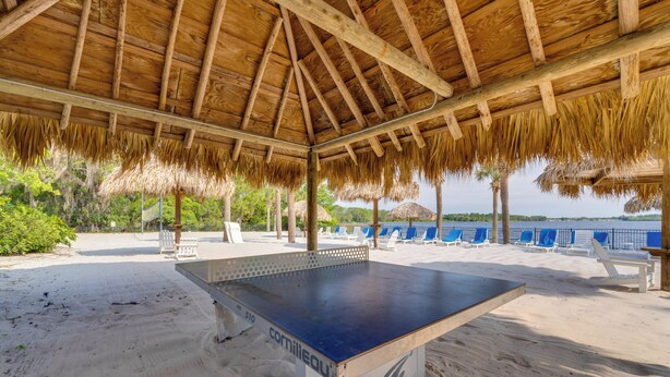 A beachside table tennis table under a thatched roof, surrounded by beach chairs and palm trees. - Bahama BAY Resort Near Disney! 3BR 2BA + Kitchen! (Davenport)