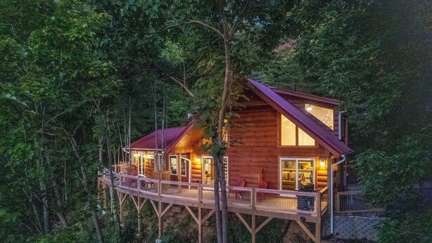 A wooden cabin with a deck, surrounded by dense forest. - Waynesville Romantic Hideaway w/ Private Hot Tub (Waynesville)