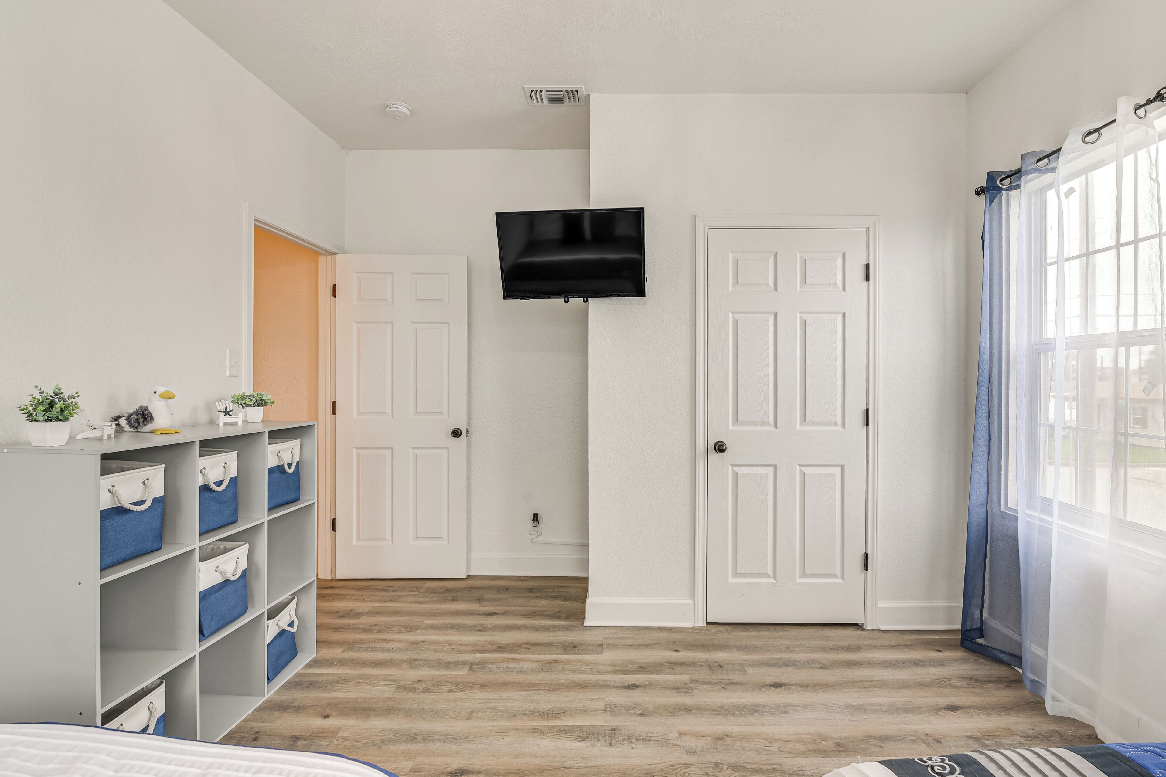 A room with a bed, a TV mounted on the wall, a wardrobe, and a door.