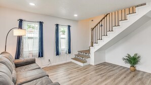 A modern living room with a staircase, wooden flooring, and a potted plant. - < 1 Mi to Beaches: Galveston Retreat w/ Patio! (Galveston)