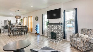 A modern living room with a fireplace, a dining area, and a kitchen in the background. - < 1 Mi to Beaches: Galveston Retreat w/ Patio! (Galveston)