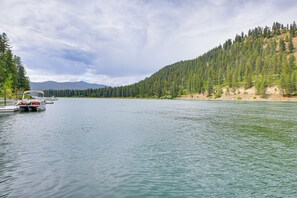 A lake with boats docked on the left, surrounded by dense forest and hills in the background.