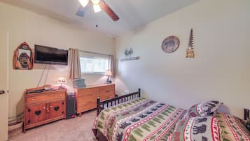 A bedroom with a bed, a dresser, a television, a ceiling fan, and wall decorations.