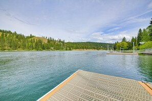 A wooden dock extending into a calm lake with a forested hillside in the background.