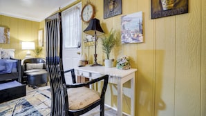A room with a sofa, a chair, a table, a lamp, a clock, and wall art. - 1 Mi to Dtwn: Fayetteville Studio w/ Patio (Fayetteville)