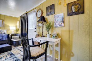 A room with a sofa, a chair, a table, a lamp, a clock, and wall art. - 1 Mi to Dtwn: Fayetteville Studio w/ Patio (Fayetteville)