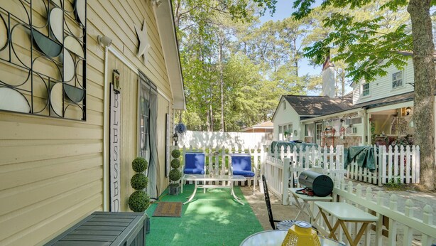 A patio with a green artificial turf, a white fence, and a white building with a chimney. - 1 Mi to Dtwn: Fayetteville Studio w/ Patio (Fayetteville)