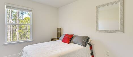 A bedroom with a bed, a window, a nightstand, and a mirror.