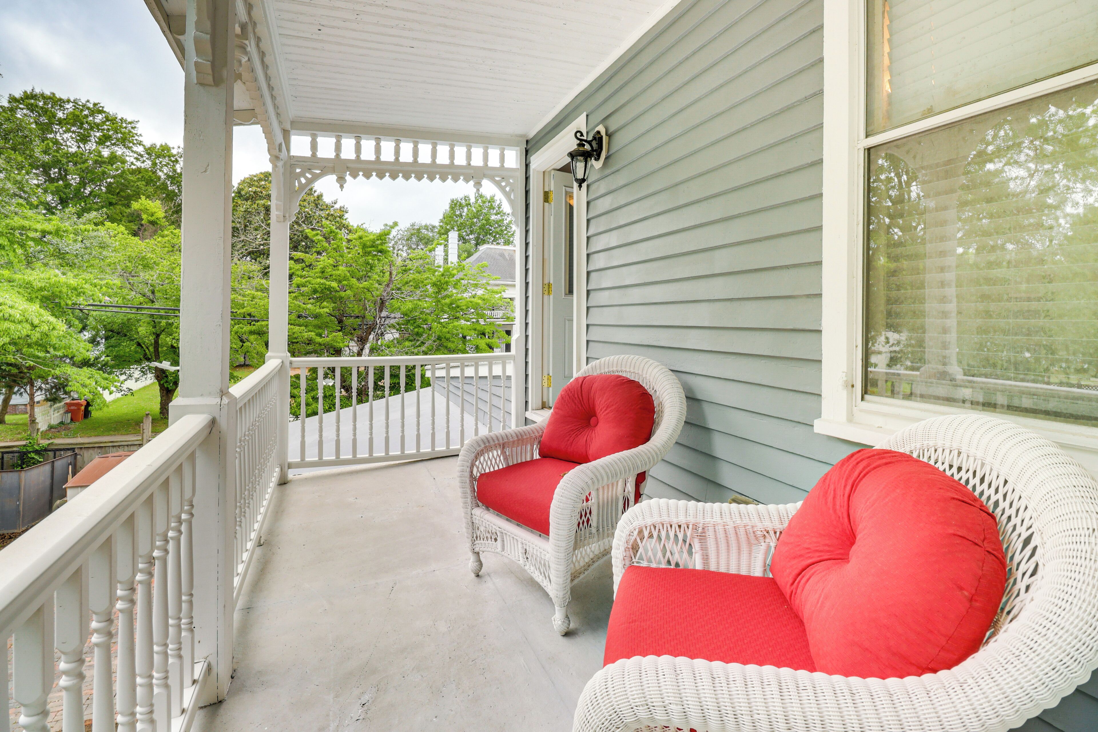 A porch with two wicker chairs and a white railing.