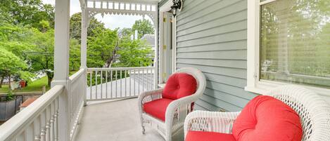 A porch with two wicker chairs and a white railing.