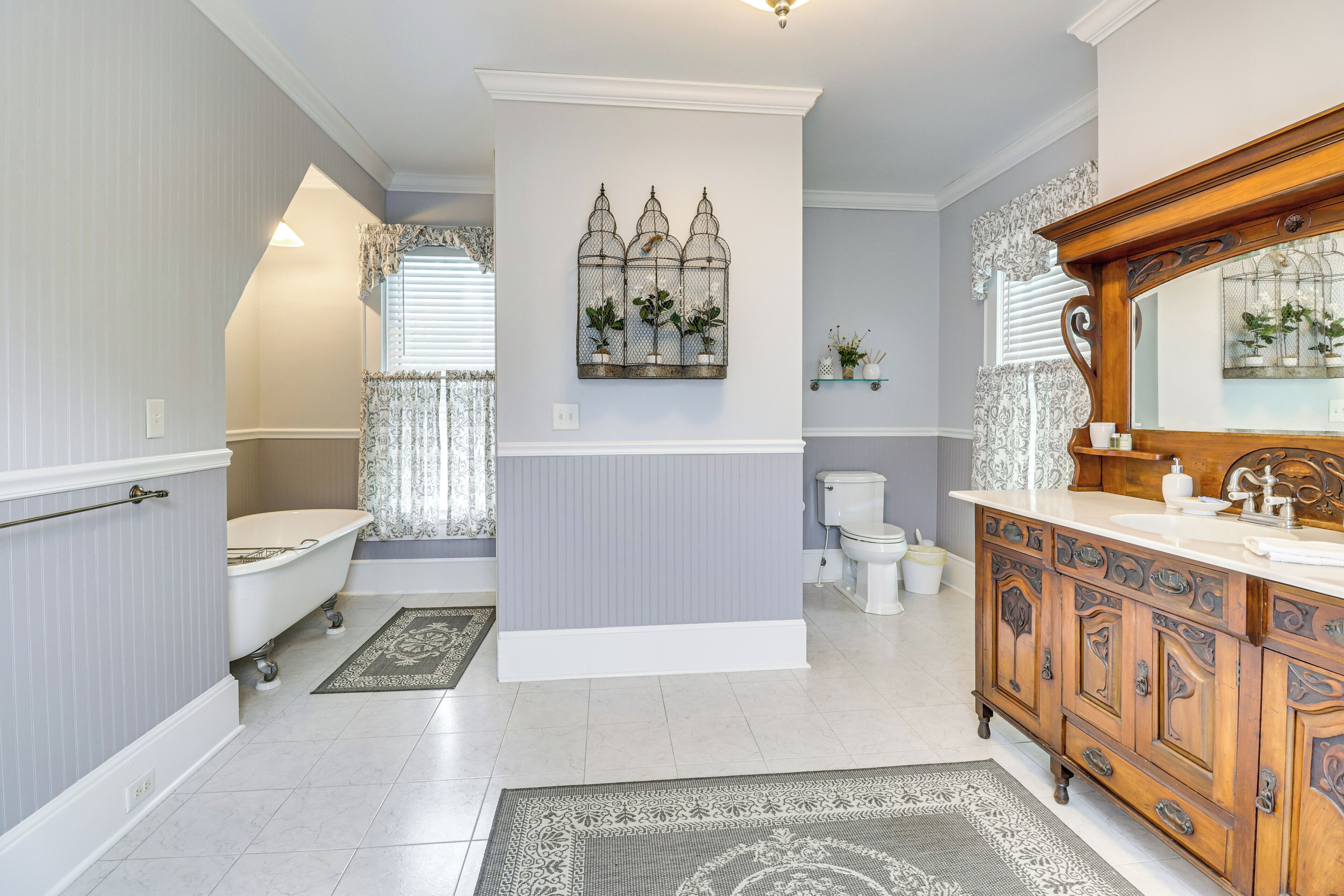 A bathroom with a freestanding bathtub, a vanity with a mirror, and a decorative wall piece.