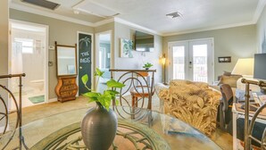 A living room with a glass coffee table, a sofa, a chair, a TV, and a desk with a computer. - Dog-friendly Getaway: Steps to Fort Myers Beach! (Fort Myers Beach)