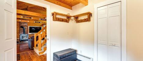 A room with a wooden ceiling, a bench, a white door, and a brick wall with a fireplace.