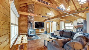Ein Holzblockhaus-Interieur mit Wohnzimmer, Küche und Kamin.
