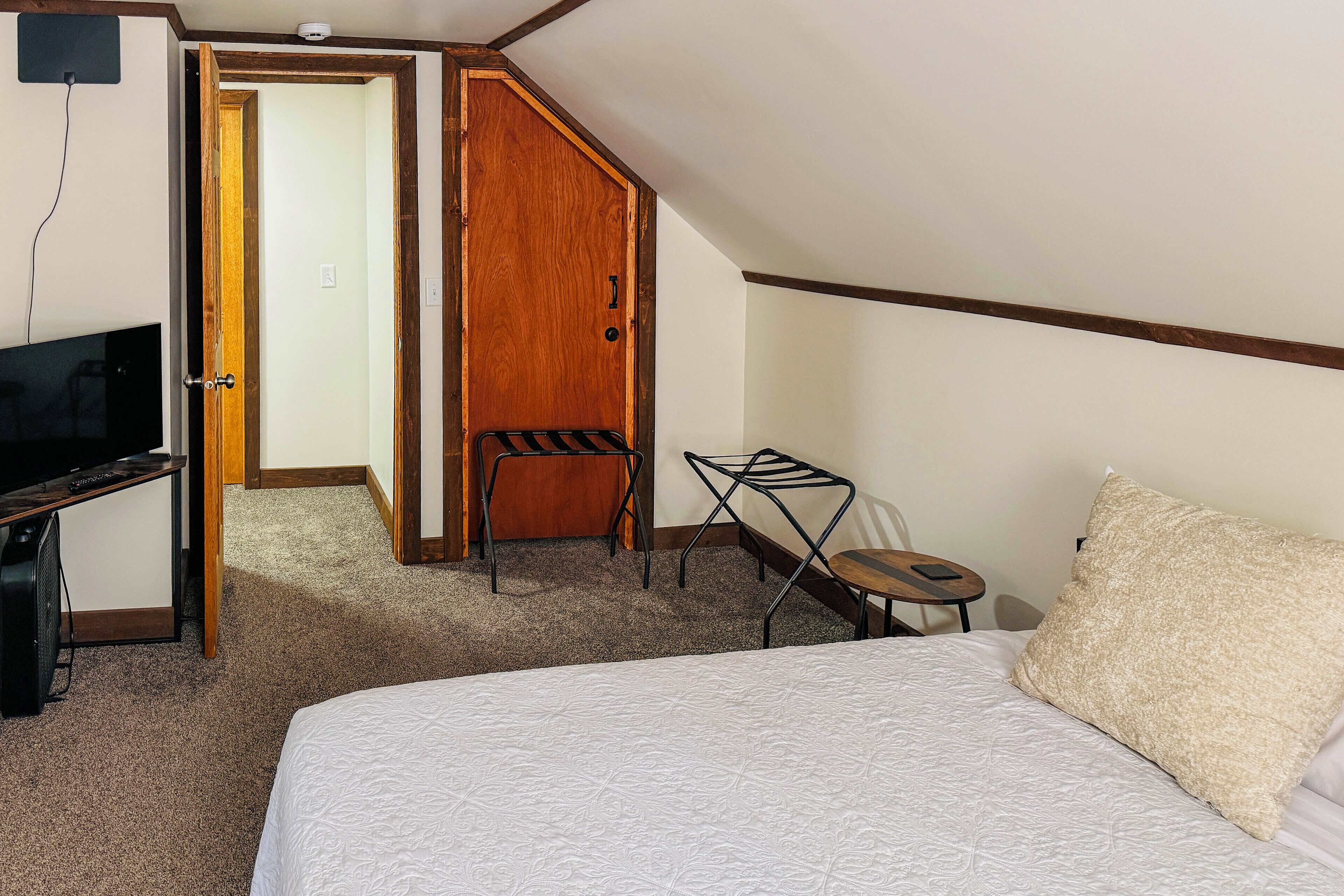Ein Hotelzimmer mit einem Bett, einem Schreibtisch mit Fernseher, einem Sessel und einem kleinen Tisch.