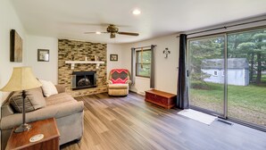 A spacious living room with a fireplace, a ceiling fan, and a large sliding glass door leading to a backyard.