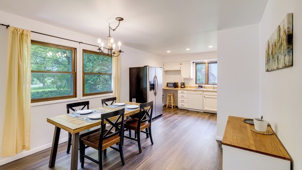 A modern kitchen with white cabinets, a wooden countertop, and a dining area with a table and chairs.