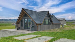 A modern house with a sloped roof, large windows, and a patio area with outdoor seating. - 1/2 Mi to Ruby River: Cabin w/ Trail Access! (Alder)