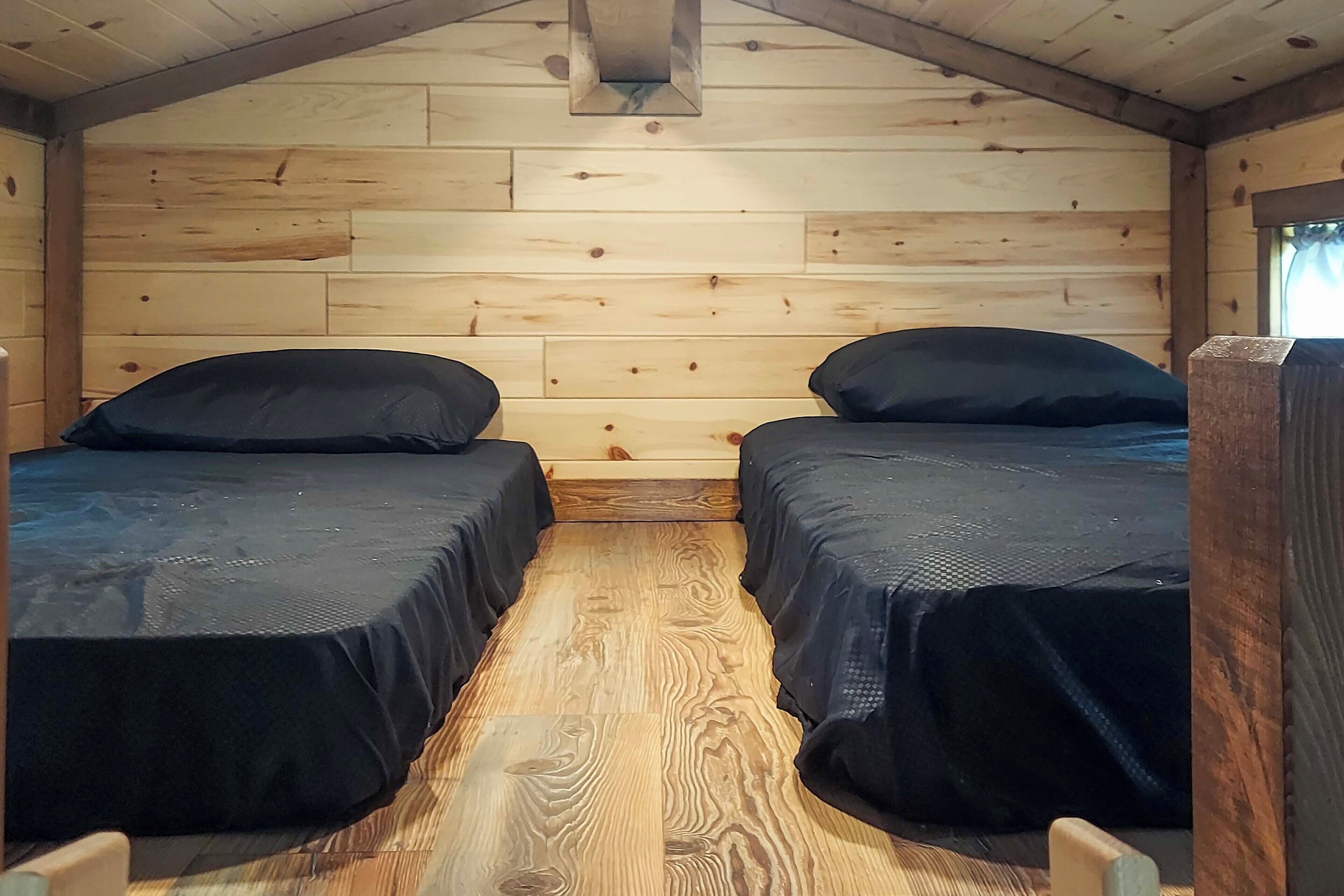 Una cabaña con dos camas, paredes de madera y techo inclinado.