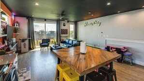 A modern living space with a wooden dining table, yellow stools, a blue sofa, and a kitchen area with a refrigerator and coffee machine. - Skyline Views: Nashville Townhome 3 Mi to Broadway (Nashville)