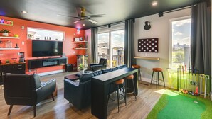 A modern living room with a TV, sofa, and bar area. - Skyline Views: Nashville Townhome 3 Mi to Broadway (Nashville)