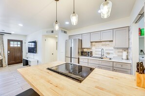 Una cucina moderna con isola centrale, elettrodomestici in acciaio inossidabile e luci a sospensione.