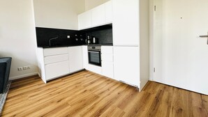 Eine moderne Küche mit weißen Schränken, einer schwarzen Arbeitsfläche und Holzboden.