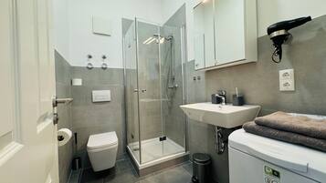 A modern bathroom with a glass-enclosed shower, a white sink, and a toilet.