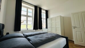 Ein Schlafzimmer mit einem Bett, einem Kleiderschrank und einem Fenster mit Vorhängen.