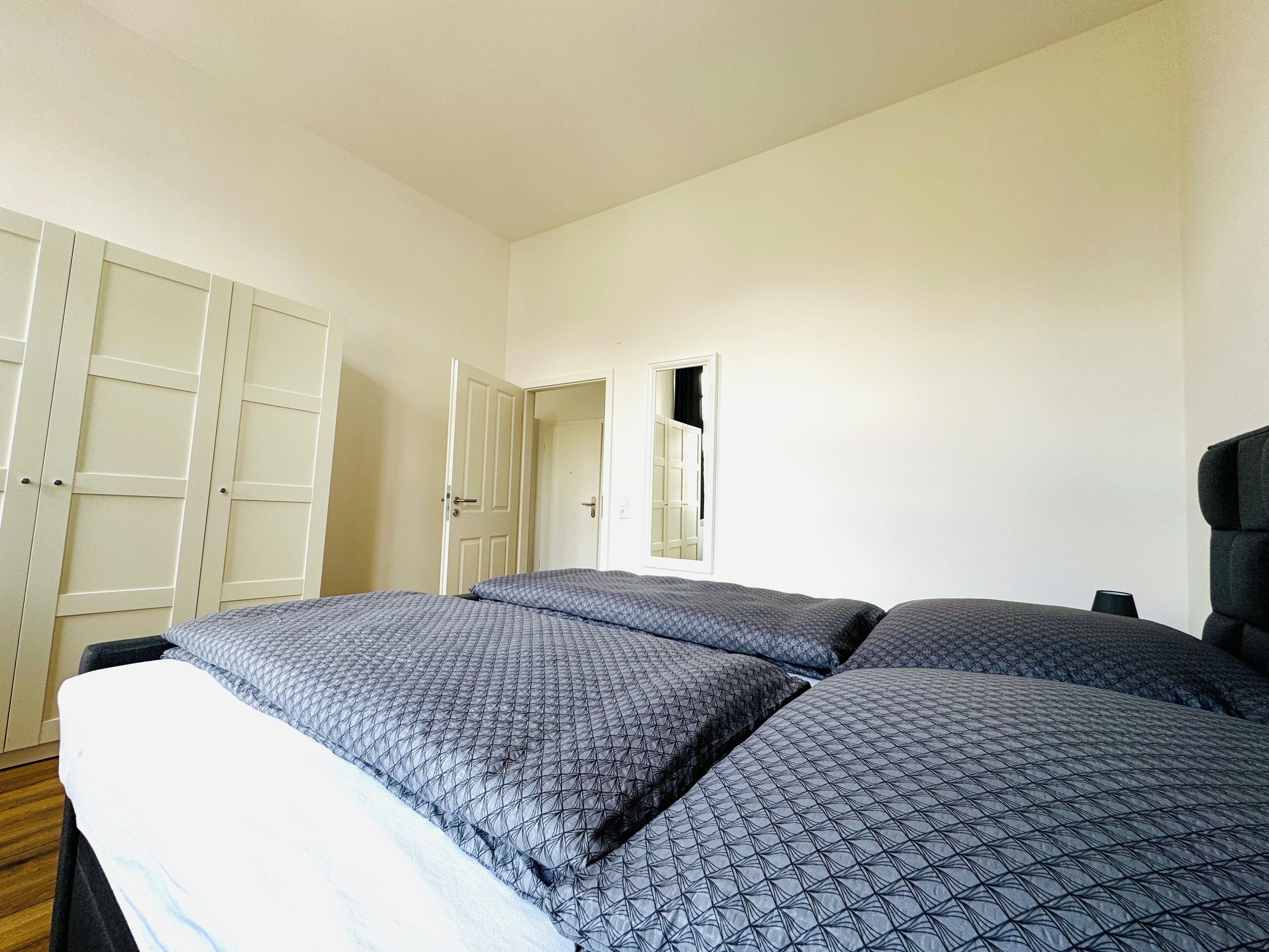 Un dormitorio con cama, armario y espejo.