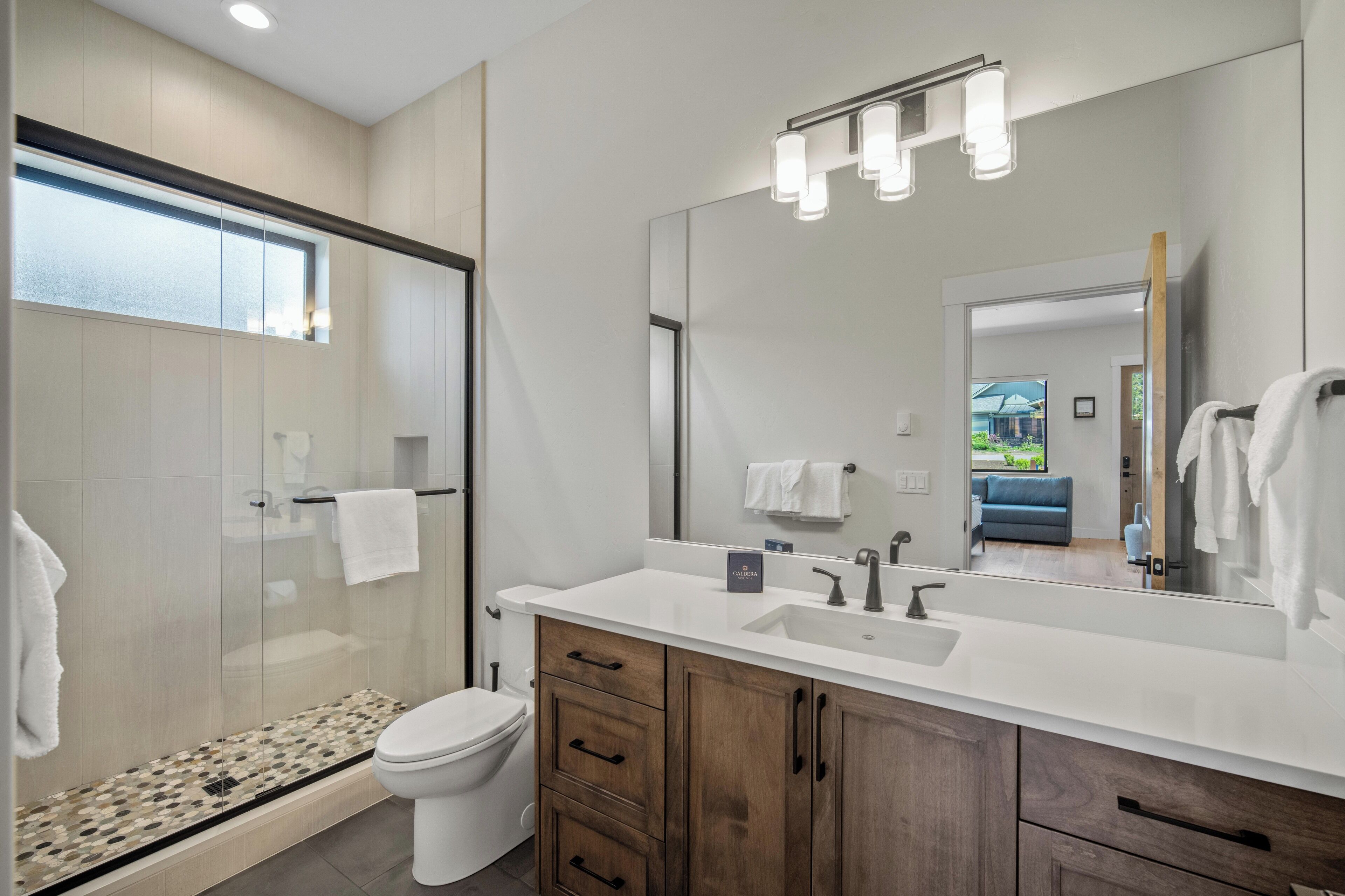 Une salle de bain moderne avec une douche à parois de verre, des toilettes blanches et des meubles en bois.