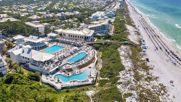 Vista aérea de un resort con múltiples piscinas, acceso a la playa y una extensa franja de arena.